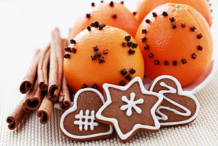cinnamon sticks, cookies, and oranges on white ceramic plate