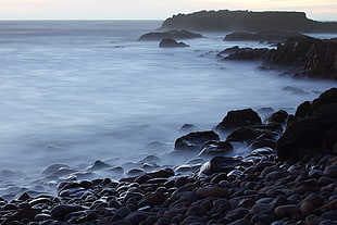 body of water beside gray rocks