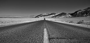 grayscale photography of pavement road near mountain