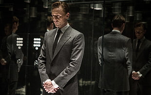 man in gray suit jacket standing inside elevator