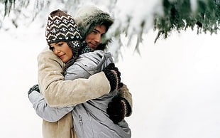 man in gray coat embracing woman in white coat HD wallpaper