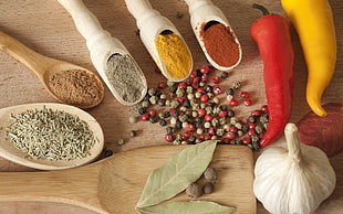bulb of garlic beside two red and yellow bell peppers and condiments powder