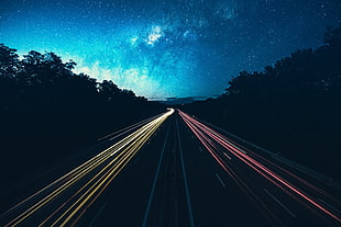 time lapse photography of road with vehicles beside trees during nighttime