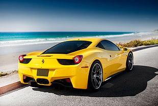yellow Ferrari sports car on road beside seashore