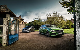 photo of two green and gray Mercedes-Benz cars near opened blue gate