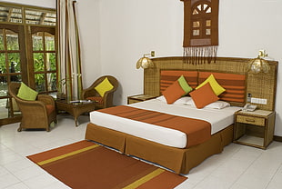 white and brown bedspread beside rattan frame sofa chairs
