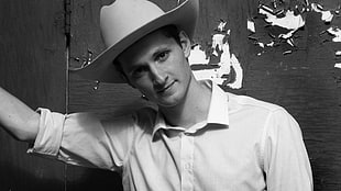 grayscale photography of man wearing cowboy hat and collared shirt