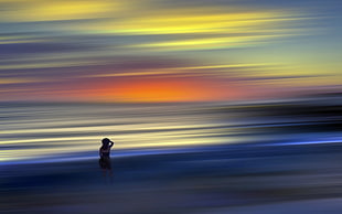 silhouette photography of woman near beach during sunset