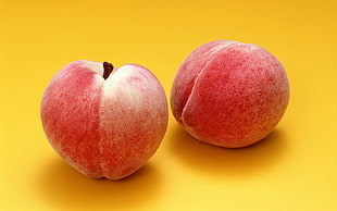 photo of two red peaches on yellow surface HD wallpaper