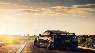 black Nissan sports coupe on black concrete road during sunset