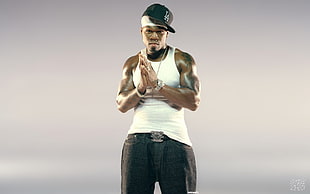 male rapper wearing white tank top, black bottoms and flat brim cap