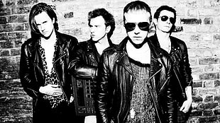 gray scale of four men wearing a black leather zip-up jacket