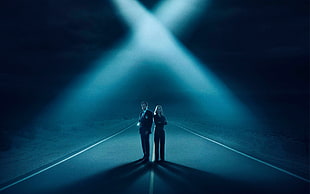 man and woman in black suits standing on the center of the road