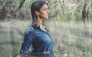 woman walking on lagoon wearing blue chambray button-up dress shirt during daytime HD wallpaper