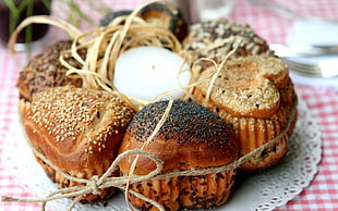heart baked bread with white candle placed on white and red table arrangement in closeup photography