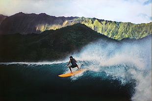 man riding surf on sea near mountain, hawaii