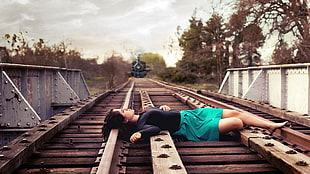 woman lying on train rail during daytime