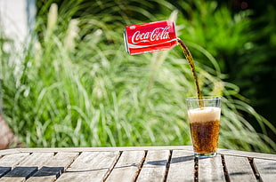 floating red coca-cola can transferring into drinking glass