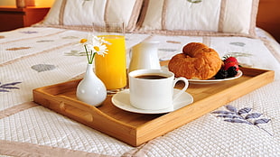 brown wooden tray with baked bread, fruits, juice, and coffee
