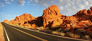 asphalt road surrounded by brown rocks and mountains