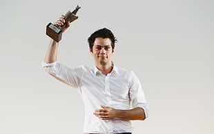 man in white button-up dress shirt holding brown trophy