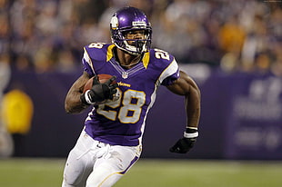 man in purple jersey holding football on game HD wallpaper