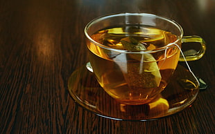 clear glass teacup filled with tea place on table HD wallpaper
