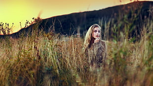 woman wearing gray jacket in the middle of grass field during day time