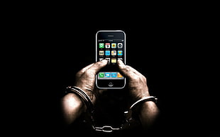 person with handcuffs holding iPhone 3gs