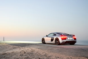 silver Audi R8 on beach in distant of lighthouse