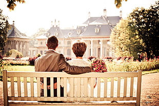 couple sitting on bench facing house during daytime HD wallpaper
