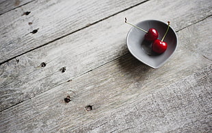 two red cherries on gray saucer