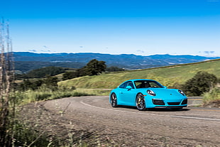 blue Porsche coupe on gray road