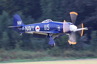 blue and white Navy 115 propeller plane flying in daytime