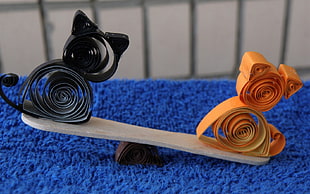 black and orange cat origami on brown popsicle seesaw