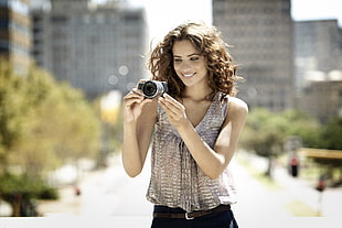 woman holding DSLR camera while smiling taking photo