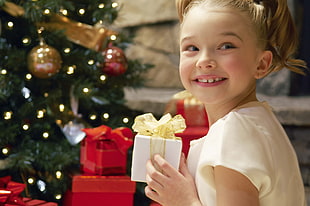 girl wear white shirt and hold white gift box while smile