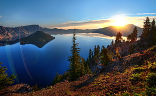 brown mountain beside body of water during sunset HD wallpaper