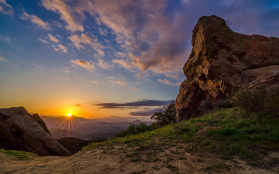 brown rock under cloudy sky during golden hour HD wallpaper