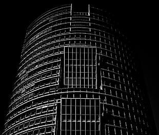 grayscale architectural shot of round high rise building