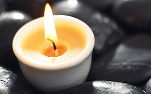 lighted candle near black stones