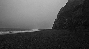 grayscale photography of person on bech, black sand, shore