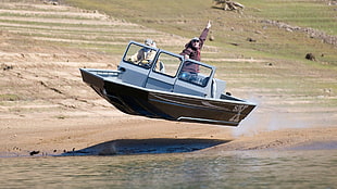 two person riding a brown powerboat going through the body of water