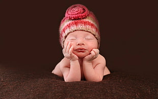 baby wearing red and brown knitted beanie hat