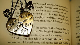 photo of silver-colored heart pendant necklace on top of book