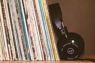 black stereo headphones beside vinyl album sleeve cases on shelf