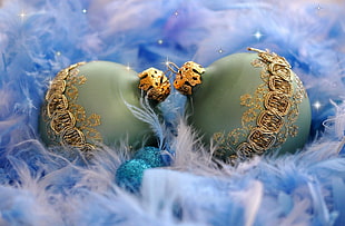 two green-and-brown christmas baubles on white and blue fur
