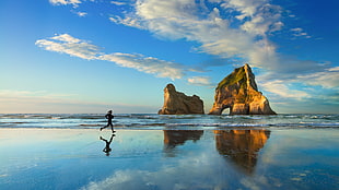person running beside seashore under white clouds and blue sky