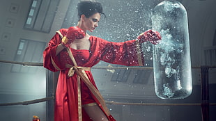 woman in red boxer robe wearing boxing gloves punching clear water heavy bag movie scene