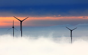 silhouette photo of three windmills surrounded by fogs